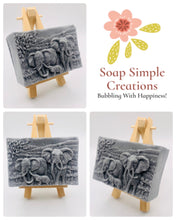 Load image into Gallery viewer, Handmade vegan soap featuring an elephant family with baby elephant and packed in beautiful eco friendly packaging. crafted with natural French clays, activated charcoal and essential oils. a eco-friendly, zero waste gift that’s cruelty-free, skin-nourishing, and perfect for elephant lovers or animal themed gifts. Small business UK