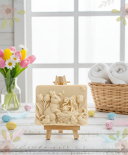 Load image into Gallery viewer, Intricate handmade soap scene from Soap Simple Creations featuring an Easter bunny, chicks, and tulips, displayed on a wooden easel with spring flowers. Vegan and cruelty free soap.