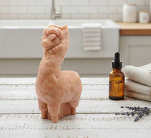Load image into Gallery viewer, Decorative llama / alpaca vegan soap on a wooden surface with a bottle and lavender sprigs in the background.