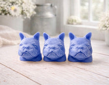 Load image into Gallery viewer, three french bulldog-head shaped bars of soap, side-by-side, on a wooden surface, set in a cozy, rustic bathroom with a vase of white and yellow flowers