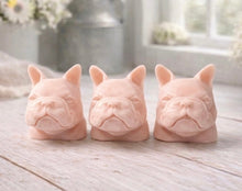 Load image into Gallery viewer, three french bulldog-head shaped bars of soap, side-by-side, on a wooden surface, set in a cozy, rustic bathroom with a vase of white and yellow flowers