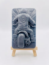 Load image into Gallery viewer, detailed handmade vegan soap gift featuring a motorcycle rider with a skull emblem on their jacket, displayed on a wooden easel against a whimsical farmhouse decor background