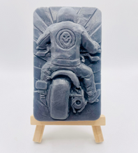 Load image into Gallery viewer, detailed handmade vegan soap gift featuring a motorcycle rider with a skull emblem on their jacket, displayed on a wooden easel against a whimsical farmhouse decor background