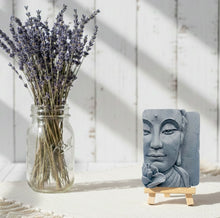 Load image into Gallery viewer, handmade vegan soap featuring a detailed 3D relief of a serene Buddha face with a lotus flower, displayed on a wooden easel against a whimsical farmhouse decor background.