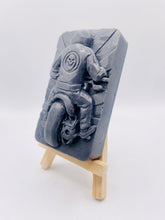 Load image into Gallery viewer, detailed handmade vegan soap gift featuring a motorcycle rider with a skull emblem on their jacket, displayed on a wooden easel against a whimsical farmhouse decor background