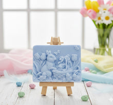 Load image into Gallery viewer, Intricate handmade soap scene from Soap Simple Creations featuring an Easter bunny, chicks, and tulips, displayed on a wooden easel with spring flowers. Vegan and cruelty free soap.