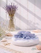 Load image into Gallery viewer, A handmade vegan soap featuring two grey dolphins jumping through white frothy waves; the base is white, and the dolphins are highly detailed, displayed on a light wooden surface against a soft farmhouse background.