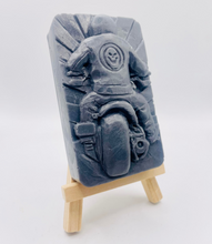 Load image into Gallery viewer, detailed handmade vegan soap gift featuring a motorcycle rider with a skull emblem on their jacket, displayed on a wooden easel against a whimsical farmhouse decor background
