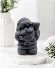 Load image into Gallery viewer, A highly detailed 3D handmade vegan soap featuring a Father Christmas carrying a large sack of gifts over his shoulder and holding a bell, featuring an intricate curly beard and fur-trimmed suit, set against a festive holiday background.