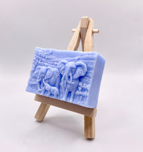 Load image into Gallery viewer, Handmade vegan soap featuring an elephant family with baby elephant and packed in beautiful eco friendly packaging. crafted with natural French clays, activated charcoal and essential oils. a eco-friendly, zero waste gift that’s cruelty-free, skin-nourishing, and perfect for elephant lovers or animal themed gifts. Small business UK