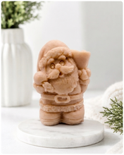 Load image into Gallery viewer, A highly detailed 3D handmade vegan soap featuring a Father Christmas carrying a large sack of gifts over his shoulder and holding a bell, featuring an intricate curly beard and fur-trimmed suit, set against a festive holiday background.