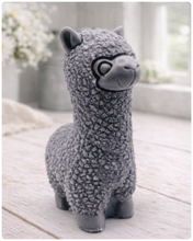 Load image into Gallery viewer, handmade vegan soap in the shape of a realistic standing alpaca sculpture, featuring detailed curly wool texture and a smiling face, displayed on a rustic white wooden surface in a bright farmhouse decor setting.