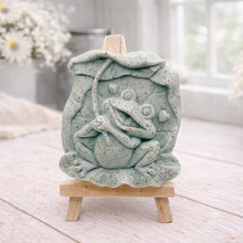 Load image into Gallery viewer, A rectangular handmade vegan soap featuring a high-relief carving of a cheerful, smiling frog sitting on a large lilypad and holding the stem of a leaf over its head like an umbrella.