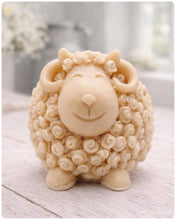 Load image into Gallery viewer, A highly detailed handmade vegan soap sculpted in the shape of a sturdy ram with a thick coat of tight, curly wool and large, elegant curved horns, displayed on a light wooden surface in a bright farmhouse setting.