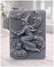 Load image into Gallery viewer, handmade vegan soap bar featuring a detailed relief carving of a witch flying on a broomstick past a crescent moon, owls, and pumpkins.