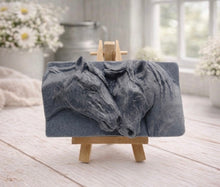 Load image into Gallery viewer, A rectangular handmade vegan soap featuring a detailed relief of two horse heads leaning affectionately towards each other, finished in soft natural tones and displayed on a miniature wooden easel.