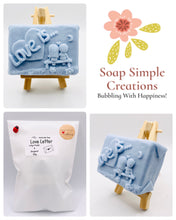 Load image into Gallery viewer, Handmade vegan soaps featuring a boy and girl sat on a bench with the wording Love Is... , in beautiful eco friendly packaging. crafted with natural French clays, activated charcoal and essential oils. a eco-friendly, zero waste gift that’s cruelty-free, skin-nourishing, the perfect gift for Valentines day or anniversary gift. small business UK