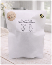 Load image into Gallery viewer, White soap bag with a label for Happy Alpaca/Llama soap on a light wooden surface.