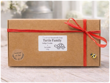 Load image into Gallery viewer, Gift box with a red ribbon and 'Turtle Family' label on a wooden surface