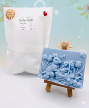 Load image into Gallery viewer, Intricate handmade soap scene from Soap Simple Creations featuring an Easter bunny, chicks, and tulips, displayed on a wooden easel with spring flowers. Vegan and cruelty free soap.