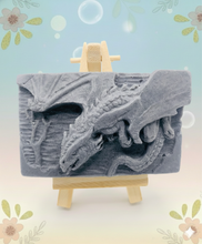 Load image into Gallery viewer, Dragon gift. Dinosaur gift. Our Flying Dragon soap features a striking dragon with its majestic wings spread wide, symbolising freedom and power. This artisan bar is vegan, cruelty-free, and designed with care for both your skin and the planet. Available in your choice of colour and essential oil. Each soap comes beautifully wrapped in eco friendly packaging. zero waste gift. kodern gift ideas. handmade home style. eco conscious home. eco friendly gifts. go green home.