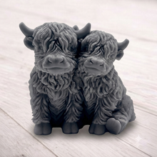 Load image into Gallery viewer, Handmade soap featuring two Highland cows with textured, shaggy fur sitting side by side on a light wooden surface with a softly indoor background.