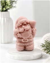 Load image into Gallery viewer, A highly detailed 3D handmade vegan soap featuring a Father Christmas carrying a large sack of gifts over his shoulder and holding a bell, featuring an intricate curly beard and fur-trimmed suit, set against a festive holiday background.