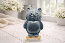 Load image into Gallery viewer, Handmade vegan soap sculpted in the shape of a round, sitting panda bear with detailed fur textures and a friendly expression, displayed on a small wooden easel.