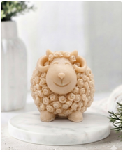 Load image into Gallery viewer, A highly detailed handmade vegan soap sculpted in the shape of a sturdy ram with a thick coat of tight, curly wool and large, elegant curved horns, displayed on a light wooden surface in a bright farmhouse setting.