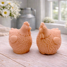 Load image into Gallery viewer, Two handmade vegan soaps in the shape of plump, realistic chicken sculptures with detailed feather textures, displayed on a rustic white wooden surface in a bright farmhouse decor setting.
