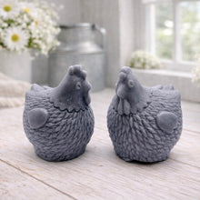 Load image into Gallery viewer, Two handmade vegan soaps in the shape of plump, realistic chicken sculptures with detailed feather textures, displayed on a rustic white wooden surface in a bright farmhouse decor setting.