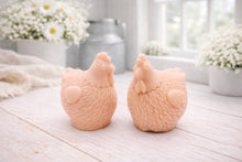 Load image into Gallery viewer, Two handmade vegan soaps in the shape of plump, realistic chicken sculptures with detailed feather textures, displayed on a rustic white wooden surface in a bright farmhouse decor setting.
