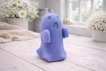 Load image into Gallery viewer, Handmade vegan soap ghost gift with a surprised expression, displayed on a light timber surface with soft white daisies in the background.