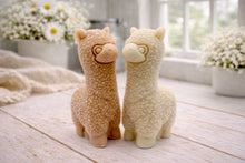 Load image into Gallery viewer, handmade vegan soap in the shape of a realistic standing alpaca sculpture, featuring detailed curly wool texture and a smiling face, displayed on a rustic white wooden surface in a bright farmhouse decor setting.