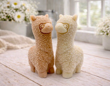 Load image into Gallery viewer, handmade vegan soap in the shape of a realistic standing alpaca sculpture, featuring detailed curly wool texture and a smiling face, displayed on a rustic white wooden surface in a bright farmhouse decor setting.