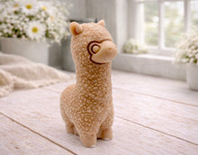 Load image into Gallery viewer, handmade vegan soap in the shape of a realistic standing alpaca sculpture, featuring detailed curly wool texture and a smiling face, displayed on a rustic white wooden surface in a bright farmhouse decor setting.