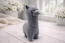 Load image into Gallery viewer, handmade vegan soap in the shape of a realistic standing alpaca sculpture, featuring detailed curly wool texture and a smiling face, displayed on a rustic white wooden surface in a bright farmhouse decor setting.
