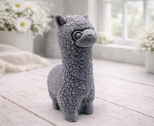 Load image into Gallery viewer, handmade vegan soap in the shape of a realistic standing alpaca sculpture, featuring detailed curly wool texture and a smiling face, displayed on a rustic white wooden surface in a bright farmhouse decor setting.