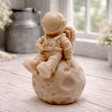 Load image into Gallery viewer, handmade vegan soap in the shape of a realistic astronaut sculpture sitting on the moon, featuring detailed spacesuit textures and craters on the lunar surface, displayed in a bright farmhouse decor setting.