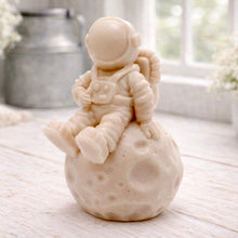 Load image into Gallery viewer, handmade vegan soap in the shape of a realistic astronaut sculpture sitting on the moon, featuring detailed spacesuit textures and craters on the lunar surface, displayed in a bright farmhouse decor setting.