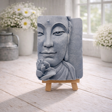 Load image into Gallery viewer, handmade vegan soap featuring a serene Buddha face relief with a lotus flower, displayed on a small wooden easel in a bright farmhouse decor setting with flowers and a rustic milk churn.