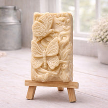 Load image into Gallery viewer, Decorative yellow French clay soap with butterfly design on a wooden stand in a bright room.