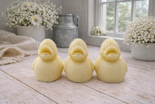 Load image into Gallery viewer, Three handmade vegan soaps in the shape of fluffy ducklings with open beaks, displayed on a neutral linen cloth in a bright farmhouse decor setting with Easter eggs in the background.