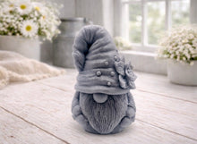 Load image into Gallery viewer, handmade vegan soap in the shape of a garden gnome sculpture with a long beard and a tall hat adorned with a large rose, displayed on a rustic white wooden surface in a bright farmhouse decor setting.