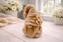 Load image into Gallery viewer, handmade vegan soap in the shape of a garden gnome sculpture with a long beard and a tall hat adorned with a large rose, displayed on a rustic white wooden surface in a bright farmhouse decor setting.