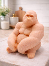 Load image into Gallery viewer, A large handmade vegan soap in the shape of a realistic sitting gorilla sculpture, featuring detailed muscular definition and skin texture, displayed on a rustic wooden surface in a farmhouse-style kitchen.