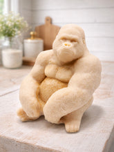 Load image into Gallery viewer, A large handmade vegan soap in the shape of a realistic sitting gorilla sculpture, featuring detailed muscular definition and skin texture, displayed on a rustic wooden surface in a farmhouse-style kitchen.