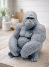 Load image into Gallery viewer, A large handmade vegan soap in the shape of a realistic sitting gorilla sculpture, featuring detailed muscular definition and skin texture, displayed on a rustic wooden surface in a farmhouse-style kitchen.