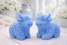 Load image into Gallery viewer, A highly detailed handmade vegan soap sculpted in the shape of a highland cow with long, flowing fur texture, a sweet face with a large snout, and prominent horns, displayed on a light wooden surface in a bright farmhouse setting.