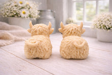Load image into Gallery viewer, A highly detailed handmade vegan soap sculpted in the shape of a highland cow with long, flowing fur texture, a sweet face with a large snout, and prominent horns, displayed on a light wooden surface in a bright farmhouse setting.